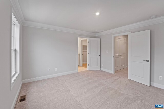 unfurnished bedroom with baseboards, light carpet, crown molding, and visible vents