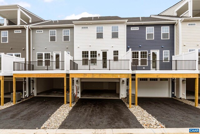 back of house featuring central air condition unit, an attached garage, and driveway