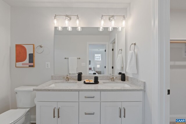 ensuite bathroom featuring double vanity, ensuite bath, toilet, and a sink