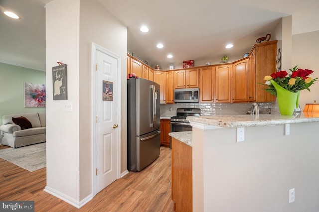  - kitchen with appliances with stainless steel finishes, a peninsula, light wood finished floors, decorative backsplash, and recessed lighting