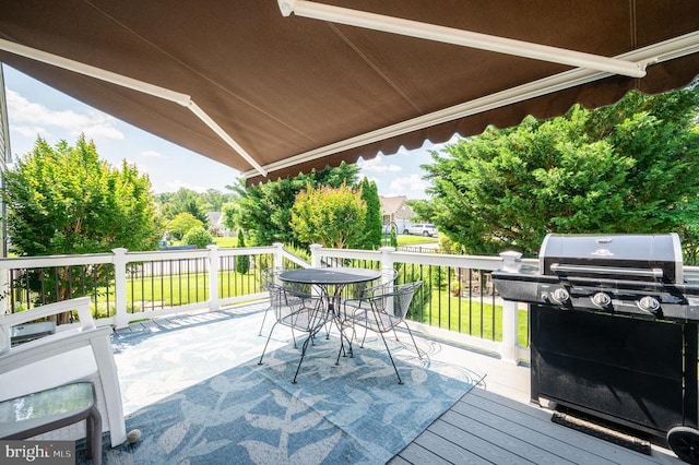  - wooden deck with area for grilling, outdoor dining space, and a lawn