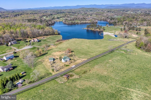 view of property location featuring a water and mountain view and a forest