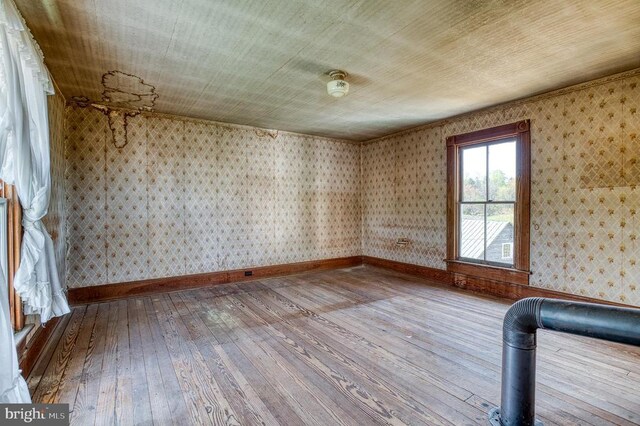 spare room with hardwood / wood-style flooring, wallpapered walls, and baseboards