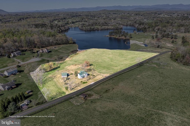 aerial view of property's location featuring a water and mountain view, a forest, and rural landscape