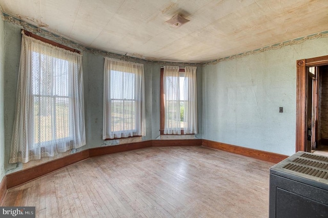 empty room with healthy amount of natural light, hardwood / wood-style flooring, and baseboards