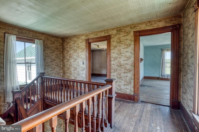 hall with an upstairs landing, hardwood / wood-style flooring, and baseboards