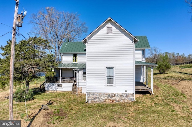 back of house with a standing seam roof, metal roof, and a lawn