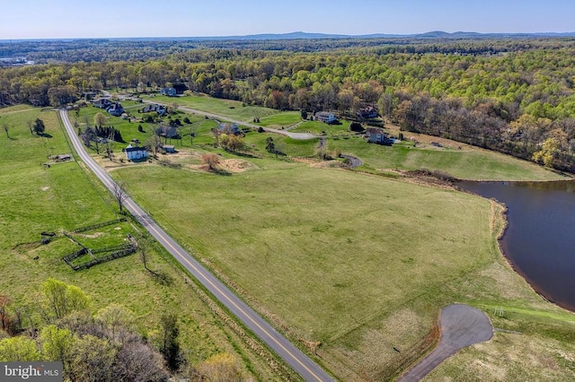 aerial view of property's location featuring a nearby body of water, rural landscape, and a heavily wooded area