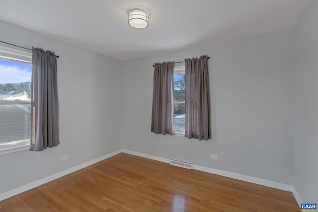 spare room with baseboards, light wood-type flooring, and visible vents