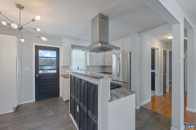 kitchen featuring freestanding refrigerator, white cabinetry, island range hood, backsplash, and a kitchen island