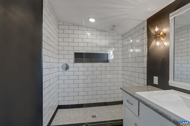 bathroom featuring vanity, lofted ceiling, and tiled shower