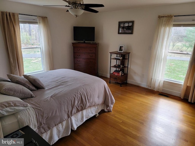  - bedroom featuring wood finished floors, multiple windows, and a ceiling fan
