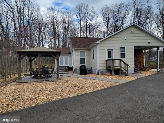  - rear view of house featuring a gazebo, a patio, and a shingled roof
