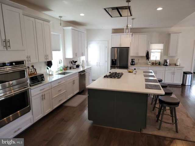  - kitchen featuring appliances with stainless steel finishes, white cabinetry, a breakfast bar, dark wood-style floors, and recessed lighting