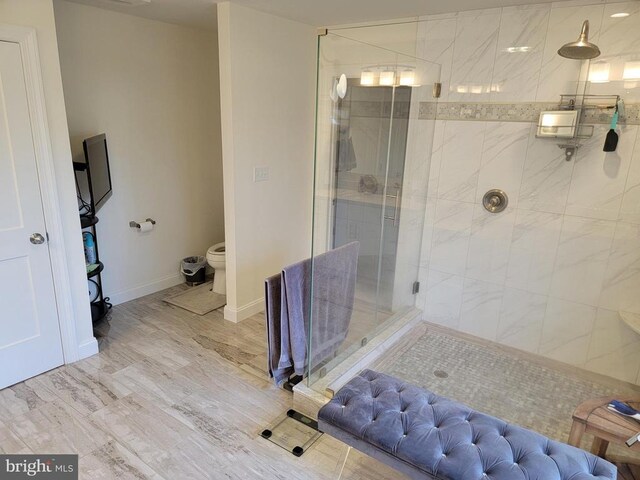  - bathroom with a shower stall, wood finished floors, toilet, and baseboards