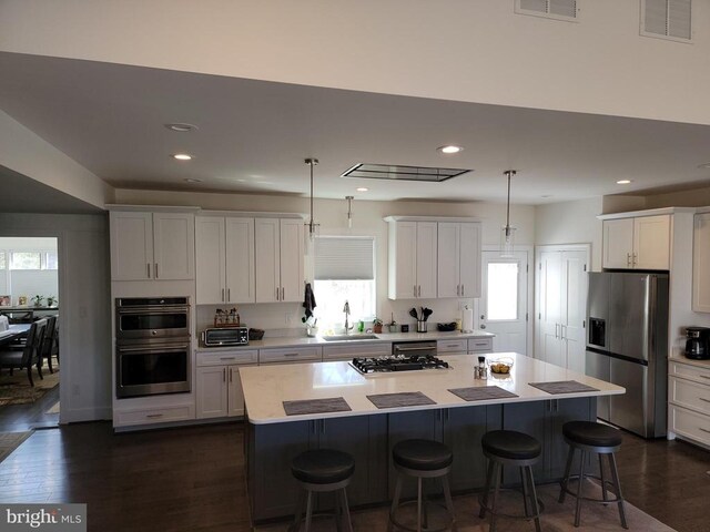  - kitchen featuring appliances with stainless steel finishes, a kitchen breakfast bar, a kitchen island, light countertops, and white cabinets