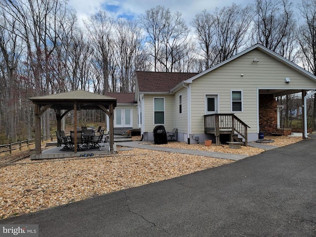  - view of front facade with a gazebo, fence, a patio area, and a shingled roof