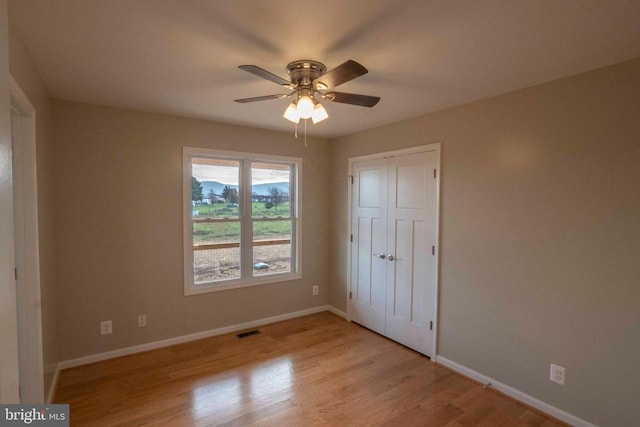 unfurnished bedroom featuring ceiling fan, a closet, and light hardwood / wood-style flooring