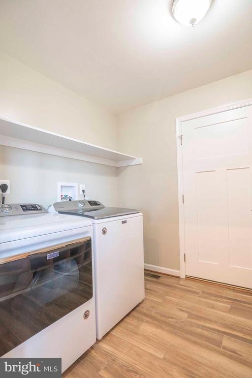 laundry area featuring light hardwood / wood-style flooring and washing machine and dryer