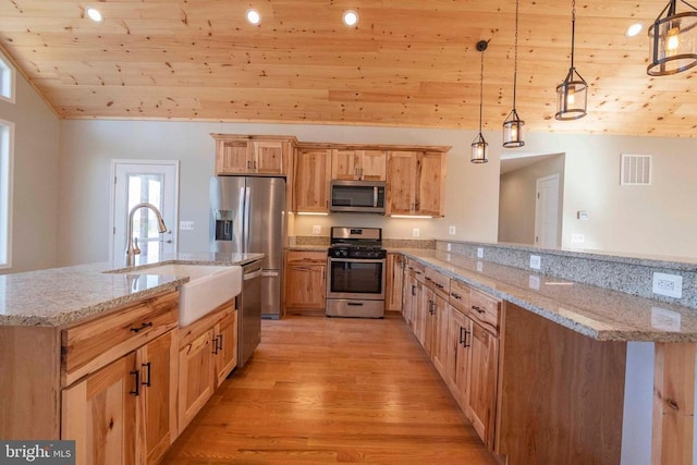 kitchen featuring pendant lighting, sink, light stone counters, and stainless steel appliances