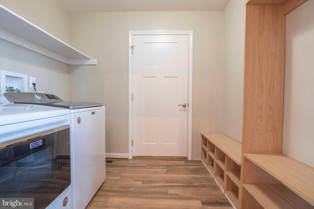 washroom with washer and clothes dryer and light hardwood / wood-style flooring