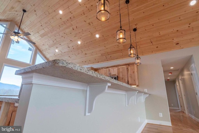 interior space with wood ceiling, light hardwood / wood-style flooring, a breakfast bar area, hanging light fixtures, and light brown cabinets