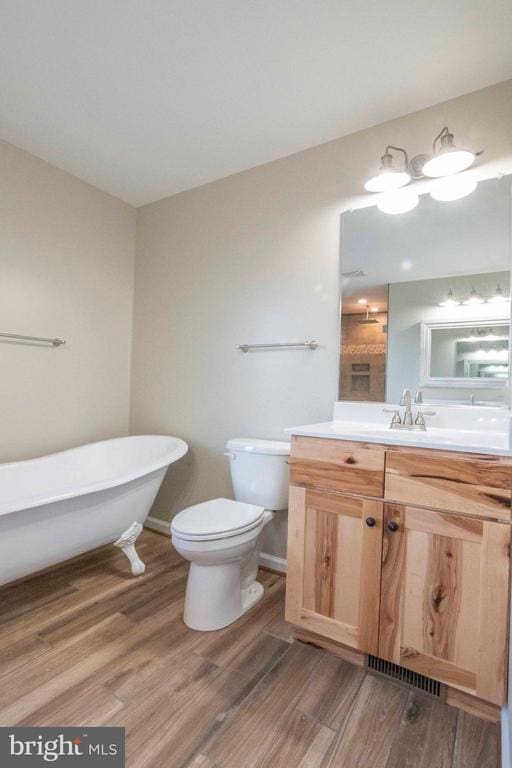 bathroom with wood-type flooring, toilet, a bathtub, and vanity