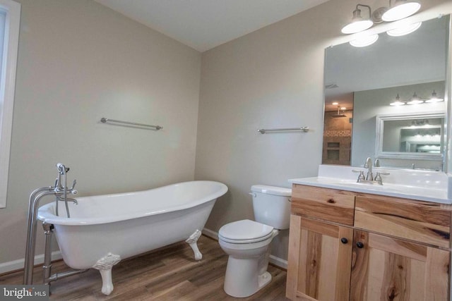 bathroom featuring vanity, a tub to relax in, hardwood / wood-style floors, and toilet