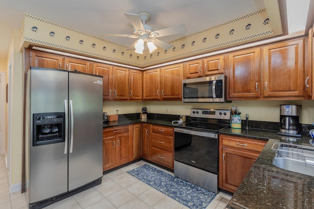 225 Divot Dr, Harrisonburg, VA 22802 - kitchen featuring appliances with stainless steel finishes, brown cabinets, a sink, dark stone counters, and light tile patterned floors