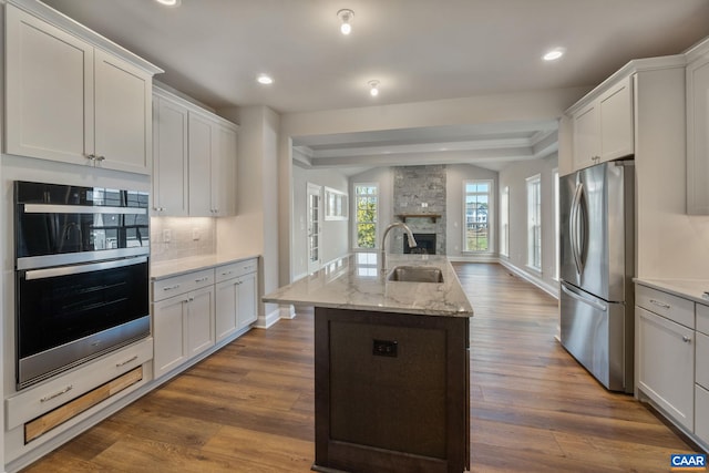 196 Thicket Run Pl, Charlottesville, VA 22911 - kitchen with freestanding refrigerator, multiple ovens, a stone fireplace, a sink, and dark wood-type flooring