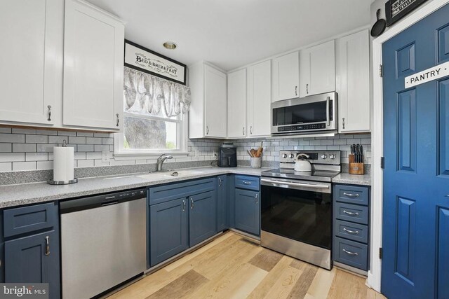 7329 Cloverhill Rd, Spotsylvania, VA 22551 - kitchen featuring stainless steel appliances, a sink, white cabinetry, light wood-style floors, and blue cabinetry