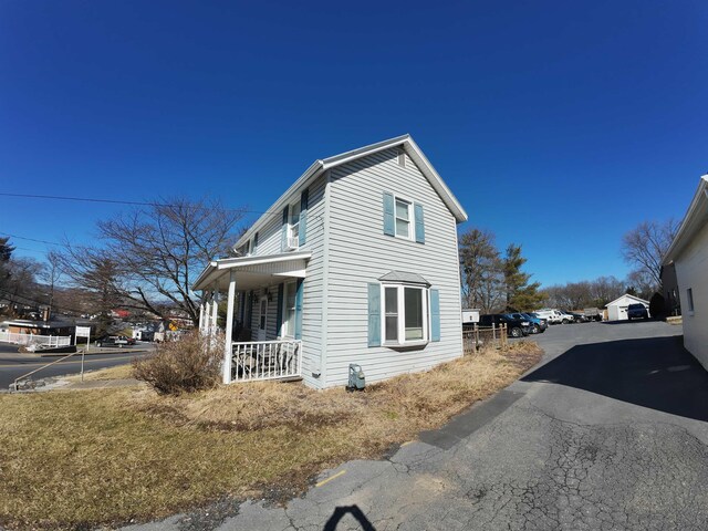 view of side of home featuring aphalt driveway and covered porch
