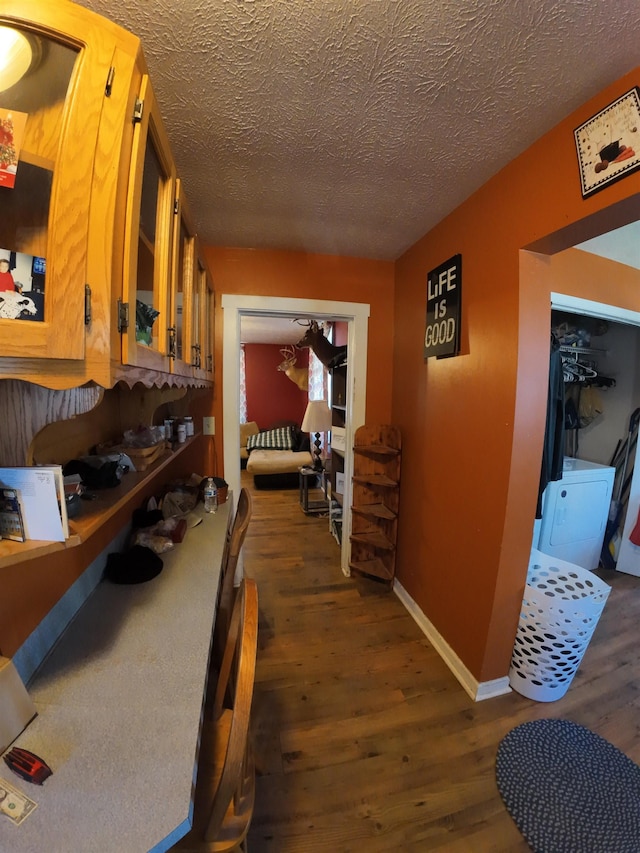 hallway with a textured ceiling, wood finished floors, and baseboards