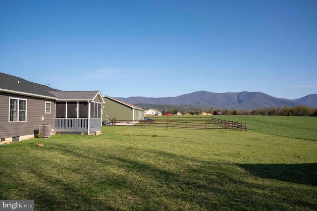 view of yard featuring a sunroom, central air condition unit, and a mountain view