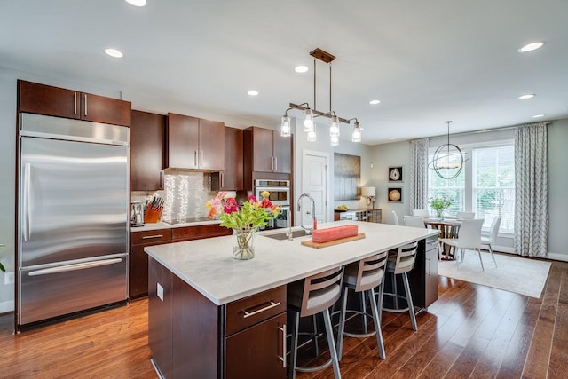 3436 Charleston Blvd, Rockingham, VA 22801 - kitchen with dark brown cabinetry, stainless steel appliances, a breakfast bar area, and a center island with sink