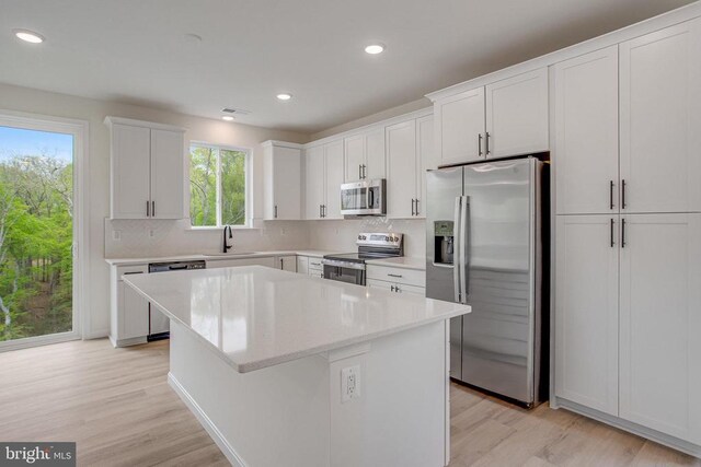 kitchen with appliances with stainless steel finishes, a sink, plenty of natural light, light wood-type flooring, and recessed lighting