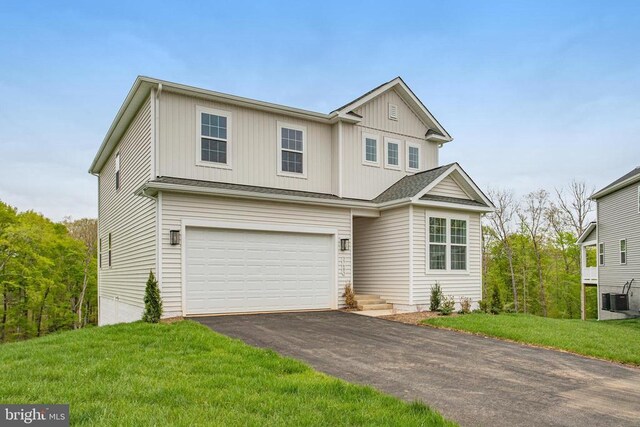 traditional-style home with an attached garage, asphalt driveway, board and batten siding, a front lawn, and central AC