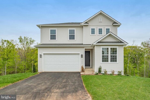 traditional-style house with asphalt driveway, an attached garage, a front yard, and board and batten siding