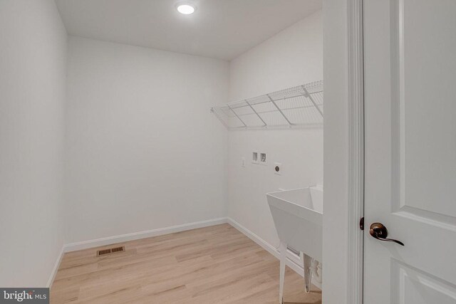 laundry area with hookup for a washing machine, electric dryer hookup, light wood-style flooring, and baseboards