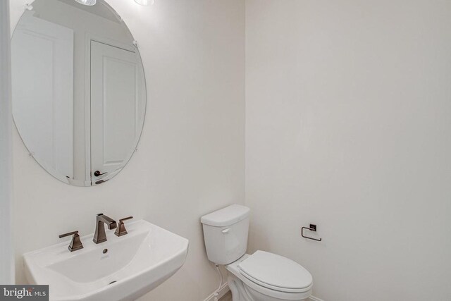 half bath with a sink, toilet, and baseboards