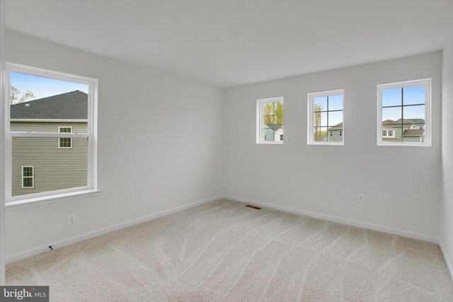 carpeted empty room featuring baseboards