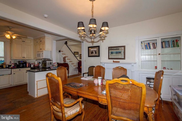 dining space with a chandelier, stairway, ceiling fan, and dark wood-style floors
