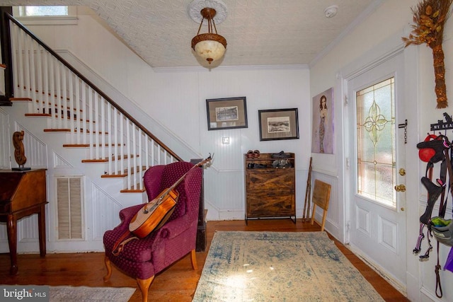 foyer entrance featuring ornamental molding, wood finished floors, healthy amount of natural light, and stairs