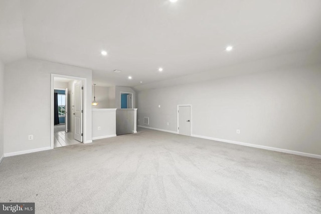 unfurnished living room with vaulted ceiling, baseboards, visible vents, and light carpet