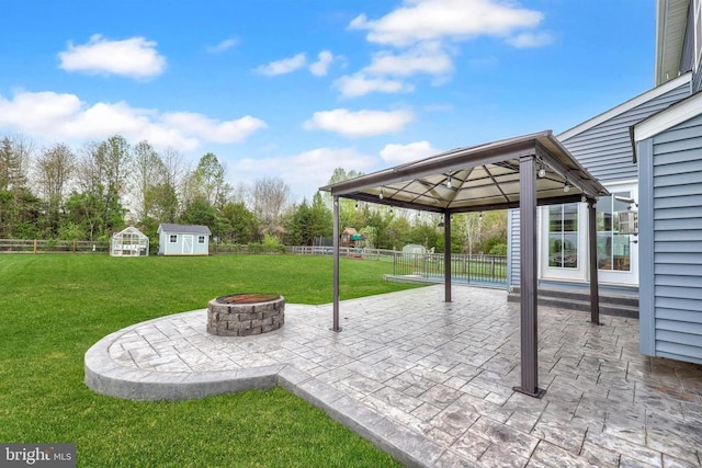 view of patio featuring a storage unit, a gazebo, an outdoor fire pit, and a fenced backyard