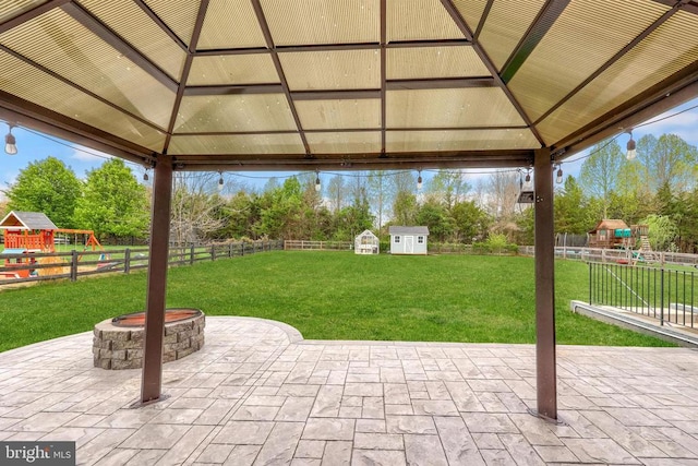 view of patio / terrace with a storage unit, an outdoor fire pit, a playground, a gazebo, and a fenced backyard