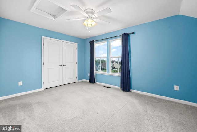 unfurnished bedroom with baseboards, a closet, attic access, and carpet