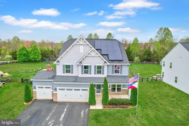craftsman-style house with roof with shingles, fence, driveway, a front yard, and solar panels