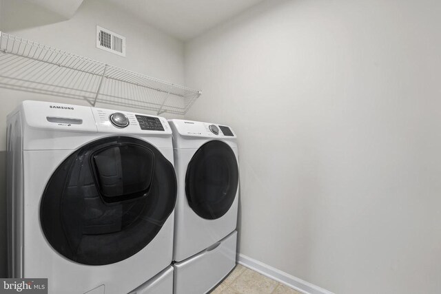 clothes washing area with separate washer and dryer, laundry area, visible vents, and baseboards