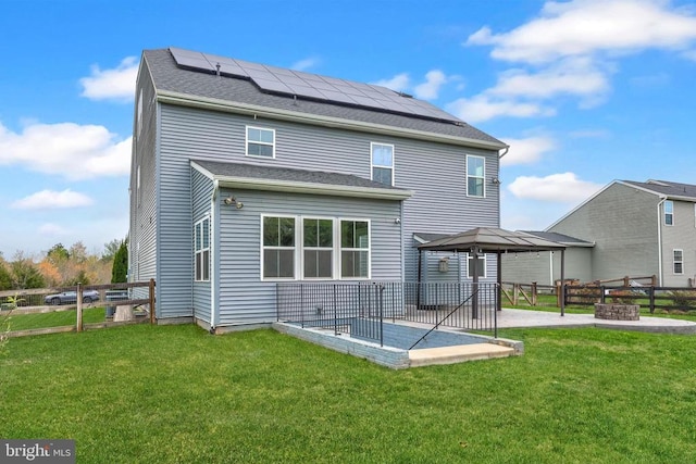 back of property with a gazebo, fence, a patio, solar panels, and a lawn